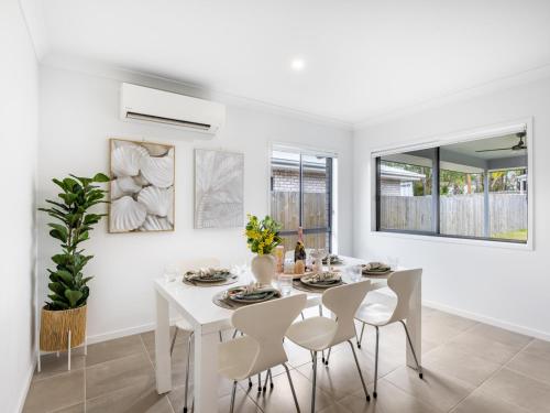 a white dining room with a white table and chairs at 4BR Newly furnished Cozy house Brownsplain in Browns Plains