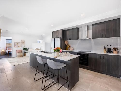 a kitchen with a large island with bar stools at 4BR Newly furnished Cozy house Brownsplain in Browns Plains