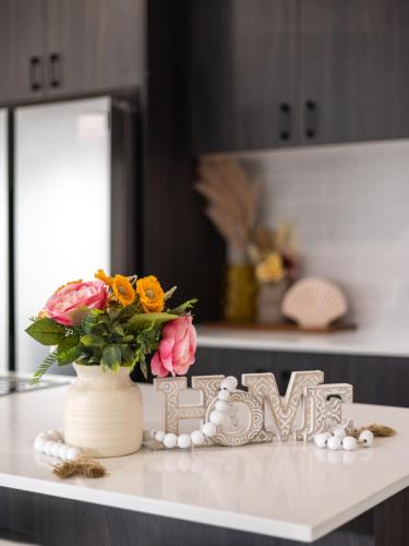 a table with a vase of flowers and a sign at 4BR Newly furnished Cozy house Brownsplain in Browns Plains