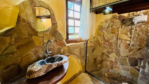 La salle de bains en pierre est pourvue d'un lavabo et d'un miroir. dans l'établissement Bio Chalé Carrancas, à Carrancas
