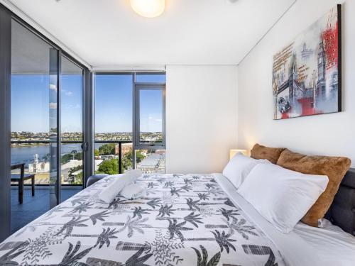 een slaapkamer met een bed en een groot raam bij Amazing cityview Glamourous 2BR Apt w parkpool in Brisbane