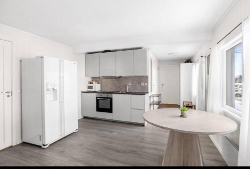 a white kitchen with a table and a white refrigerator at Modern 2-bedroom apartment 