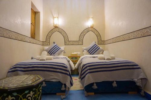 a bedroom with two beds and a mirror on the wall at Flowers riad in Marrakesh