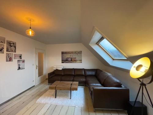 ein Wohnzimmer mit einem Ledersofa und einem Fenster in der Unterkunft Jonnys ArtApartment in Osnabrück