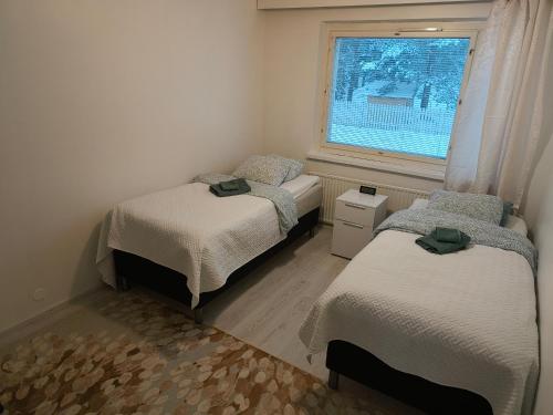 2 Betten in einem kleinen Zimmer mit Fenster in der Unterkunft Suuri huoneisto isommalle ryhmälle / Large apartment for bigger group in Tampere