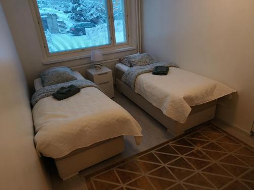 two twin beds in a room with a window at Suuri huoneisto isommalle ryhmälle / Large apartment for bigger group in Tampere