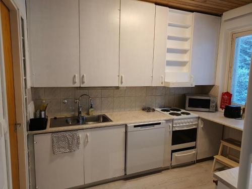 a kitchen with white cabinets and a sink and a stove at Suuri huoneisto isommalle ryhmälle / Large apartment for bigger group in Tampere