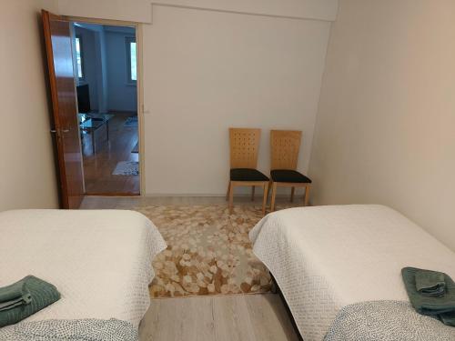 two beds in a room with two chairs and a mirror at Suuri huoneisto isommalle ryhmälle / Large apartment for bigger group in Tampere