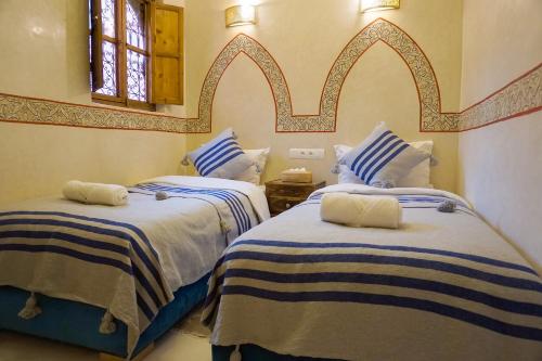 2 camas en una habitación con rayas azules y blancas en Flowers riad en Marrakech