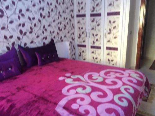 a bedroom with a pink bed with black pillows at Gessy in Salé