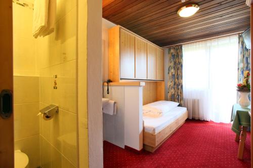 a small room with a bed and a bathroom at Alpenhotel Landhaus Küchl in Kirchberg in Tirol