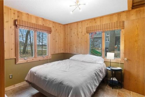 a bedroom with a bed and two windows at The Rest on the River in Cedar Falls