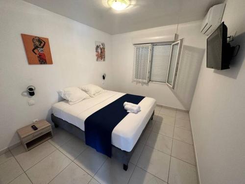 a small bedroom with a bed and a television at SLM - Le clos Gaïac - A in Saint-Laurent du Maroni