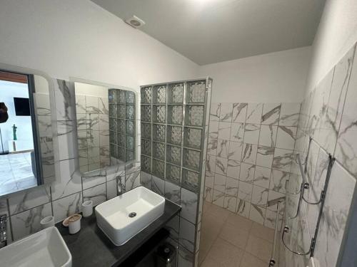 a white bathroom with a sink and a mirror at SLM - Le clos Gaïac - A in Saint-Laurent du Maroni