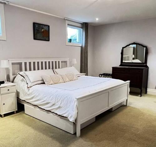 a bedroom with a large white bed and a mirror at Farmhouse Apartment Guelph Elora in Guelph