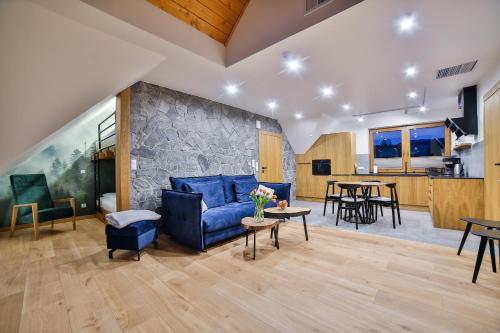 喬爾什騰的住宿－Domki Nad Osadą，客厅设有蓝色的沙发和石墙
