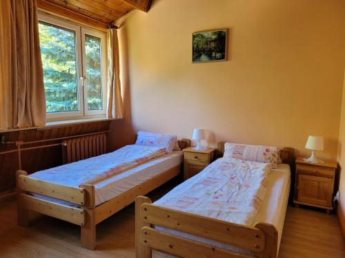 2 Einzelbetten in einem Zimmer mit Fenster in der Unterkunft Hubiza in Bukówka