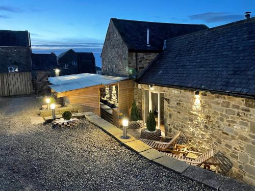 a stone building with chairs and lights in the yard at Winnie Cottage - Hot Tub, Games Room, Sauna, Large Garden in Stocksfield
