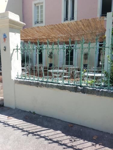 une clôture en face d'un bâtiment avec des tables et des chaises dans l'établissement Le patio de Fabio, à Bollène