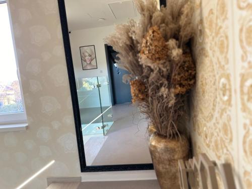 a vase with flowers in front of a mirror at Villa Mala Praha Experience in the Center of Žilina in Žilina