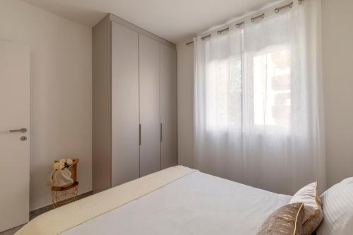 a white bedroom with a bed and a window at Lugano Superior Suites - Free Parking in Lugano