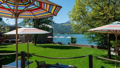 eine Terrasse mit Sonnenschirmen und einem Körper aus Wasser in der Unterkunft Cortisen am See - Adults only in St. Wolfgang