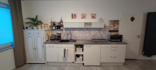 eine Küche mit weißen Schränken und einer Arbeitsplatte in der Unterkunft Erdgeschoss Koralle im Zentrum in Mönchengladbach