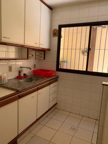uma pequena cozinha com armários brancos e um lavatório em APTO PRAIA DO MORRO, 02 QUARTOS C SUITE, WI-FI, GARAGEM, 1 ANDAR ESCADA. em Guarapari