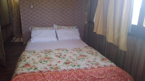 Bett mit Blumendecken und Kissen in der Unterkunft Sobradinho Nova Torres 