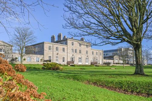an image of a large building with a tree in the foreground at 9 Admiralty House Stunning Luxury Apartment with free parking in Plymouth