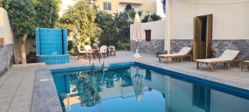 - une piscine avec des chaises, une table et un parasol dans l'établissement Senmut Luxory Apartments, à Louxor