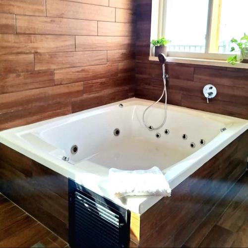 a bath tub in a bathroom with a wooden wall at בין הר ליער - צימרים באודם in Odem