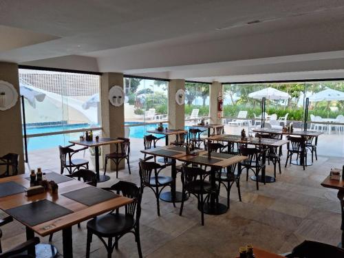 um restaurante com mesas e cadeiras e uma piscina em Praia Brava Hotel em Florianópolis