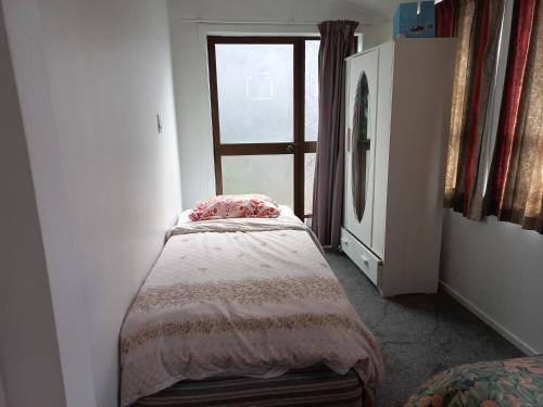 a small bedroom with a bed and a window at Central Holiday Home in Tauranga