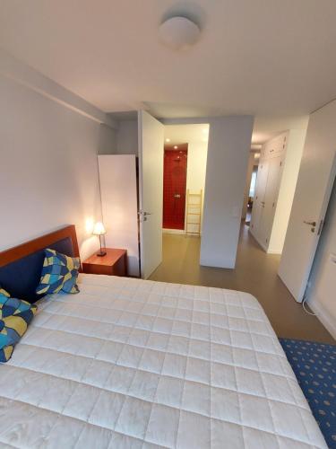 a large bedroom with a large white bed and a hallway at Santiago Rooms in Caminha