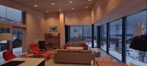 a living room with a couch and chairs and large windows at Senjavista, near nature, sea and mighty mountains in Skaland