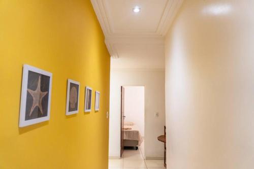 een gele muur in een gang met schilderijen erop bij PV Marimbondo's House I in Itacaré