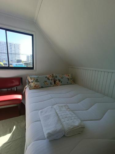 a white bed in a room with a window at Casa Huésped Los Pablos in Temuco