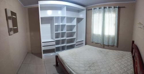 a small bedroom with a bed and a window at Casa de praia in Palhoça