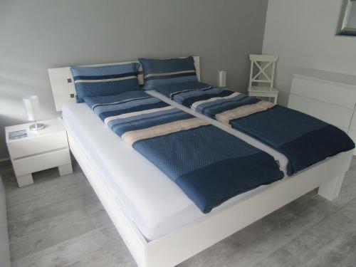 a white bed with blue blankets and pillows on it at Fewo Himmelblau in Burgen