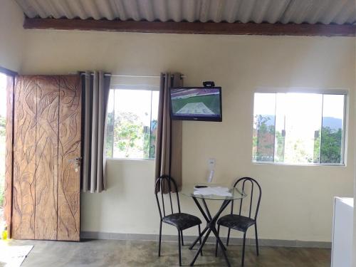 um quarto com uma mesa e duas cadeiras e uma televisão em Chalé pôr do Sol em Alto Paraíso de Goiás