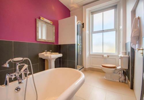 a bathroom with a tub and a toilet and a sink at Armstrong Manor in Rothbury