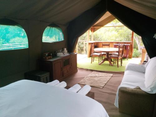 ein Schlafzimmer mit einem Zelt mit einem Tisch und Stühlen in der Unterkunft Wilderness Glamping Tents in Wilderness