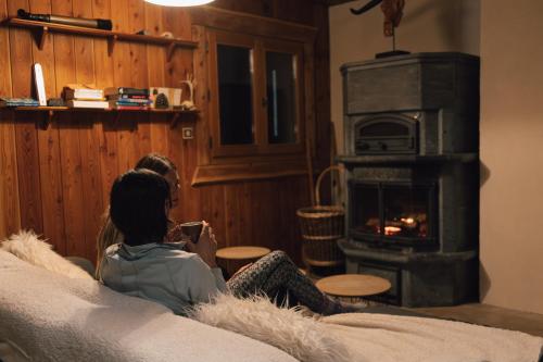 a woman sitting on a couch in front of a fireplace at Chalet d'alpage Le Lauzeron in Aiguilles