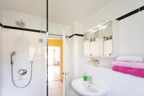 La salle de bains blanche est pourvue d'un lavabo et d'une douche. dans l'établissement Einzigartige Auszeit mit Bergblick in Bad Tölz, à Bad Tölz