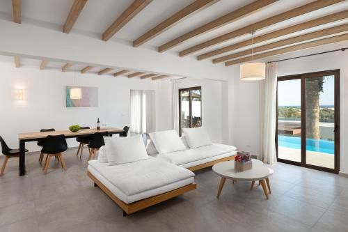 a living room with white furniture and a table at Terra Pietra Luxury Villas & Suites in Lardos