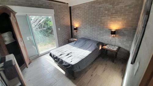 um quarto com uma cama e uma parede de tijolos em Casa en la Bota, Manantiales em Manantiales