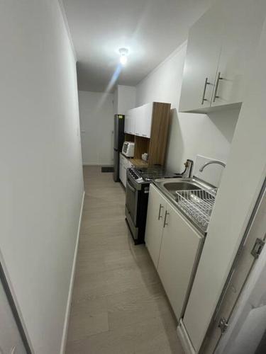 a small kitchen with a sink and a stove at Hermoso departamento con 3 dormitorios y estacionamiento in Puerto Montt