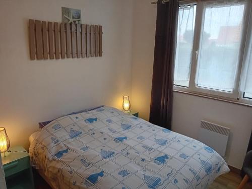 a bedroom with a bed with a comforter and a window at THALASSA in Audresselles