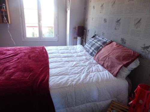 a bed with white sheets and red pillows in a bedroom at Gure Doya in Billère